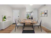 Bright dining area featuring wood-look floors, a modern table setting, and access to the kitchen at 3656 S Depew St # 102, Denver, CO 80235