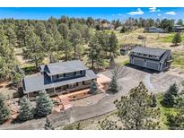 Expansive aerial view of a house with gray roof, matching detached garage, and mature landscaping including many evergreen trees at 12454 Antelope Trl, Parker, CO 80138