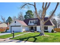 Beautifully landscaped front yard with healthy green grass and mature shade trees, showcasing home's exterior at 4970 S Chester St, Greenwood Village, CO 80111