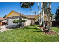 Charming yellow and brick home with a well-manicured lawn and mature trees enhancing its curb appeal at 1030 S Fulton Ave, Fort Lupton, CO 80621