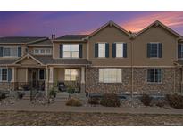 Tan two-story townhome with stone accents and a landscaped front yard at 12910 W Burgundy Dr, Littleton, CO 80127