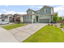 Beautiful home with a well-manicured lawn, a long driveway, and charming green siding at 17880 W 94Th Dr, Arvada, CO 80007