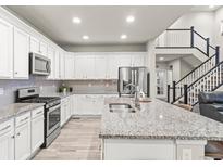 Bright kitchen features white cabinets, granite countertops, stainless steel appliances, and a spacious island at 17880 W 94Th Dr, Arvada, CO 80007