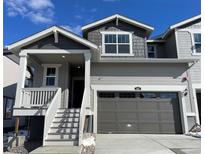 Charming two-story home with gray siding, inviting porch, and attached two car garage at 547 Nightsky St, Erie, CO 80516