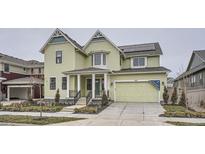 Two-story light green house with a large front porch and attached two-car garage at 1885 Hickory Ave, Erie, CO 80516