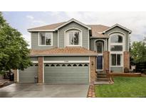 Inviting two-story home featuring a three-car garage, brick accents, and a beautifully landscaped front yard at 7700 Bison Ct, Littleton, CO 80125