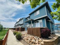 Charming blue townhome exterior with well-maintained landscaping and inviting walkway at 12036 Monaco St, Brighton, CO 80602