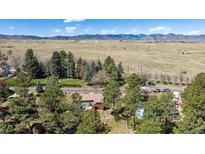 Expansive aerial shot showcasing the property, mature trees, and a backdrop of mountains in the distance at 7904 Hill Crest Dr, Louviers, CO 80131