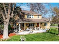 Charming yellow two-story home with a welcoming front porch, swing, and well-maintained lawn at 7835 Valley View St, Louviers, CO 80131