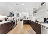 Modern kitchen featuring stainless appliances, white cabinets, backsplash and hard wood floors, perfect for cooking at 2550 Lawrence St # Rb308, Denver, CO 80205