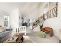 Bright living room featuring vaulted ceilings, modern furnishings, and staircase to the upper level at 11586 Chase Way, Westminster, CO 80020
