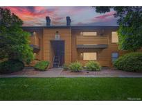 Inviting condo with wood facade, balconies, well-maintained landscaping, and a vibrant green lawn at 3315 S Ammons St # 103, Lakewood, CO 80227