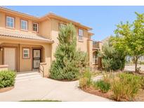 Tan two-story townhome featuring a tile roof, neutral trim, private entrance and lovely landscaping at 7777 E 23Rd Ave # 1401, Denver, CO 80238