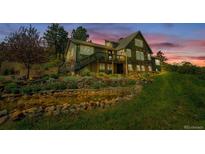 Stunning multi-level home featuring a beautifully landscaped yard with a charming water feature at twilight at 1549 Hillside Cir, Sedalia, CO 80135