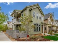 Inviting two-story home with a covered porch, balcony, gray fence, landscaped yard, and vibrant green exterior at 1754 W 66Th Ave, Denver, CO 80221