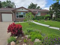Charming brick home boasts a well-manicured lawn and beautiful landscaping with vibrant flowers and mature trees at 5047 S Mabre Ct, Littleton, CO 80123