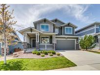 Charming two-story home featuring a covered porch, manicured lawn, and attached two car garage at 16978 W 87Th Ave, Arvada, CO 80007