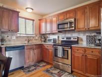 Cozy kitchen with wooden cabinets, stainless steel appliances and granite countertops at 4151 S Lewiston Cir, Aurora, CO 80013