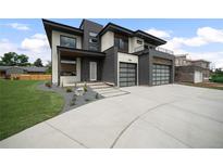 Stunning modern home showcasing a three-car garage, concrete driveway and minimalist landscaping at 5224 Lions Paw St, Castle Rock, CO 80104