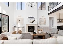 Bright living room features soaring ceilings, fireplace, stylish decor, and large windows allowing for ample natural light at 5224 Lions Paw St, Castle Rock, CO 80104