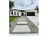 Charming single-story home with a modern walkway, black garage door and beautiful landscaping at 3065 S Birch St, Denver, CO 80222