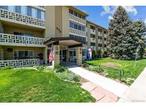 Inviting condo building showcasing professional landscaping, flags, and a covered entryway at 695 S Alton Way # 5A, Denver, CO 80247