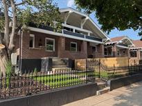 Charming brick home featuring a manicured lawn, decorative iron fence, and inviting entrance steps at 3922 W 29Th Ave, Denver, CO 80212