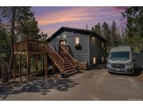Charming home featuring a wooden deck, staircase, and ample parking space near natural surroundings at 11557 Green Cir, Conifer, CO 80433