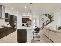 Bright, open kitchen features a large island with seating, stainless steel appliances and modern finishes at 6619 Mariposa Ct, Denver, CO 80221