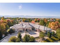 Expansive home with large driveway and meticulously landscaped front yard, against a backdrop of mountains and colorful foliage at 8833 Portico Ln, Longmont, CO 80503