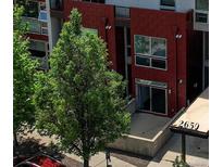 Modern exterior features a red brick facade, large windows, and a well-maintained green tree in front at 2650 W Front View Crescent Dr # 101, Denver, CO 80211