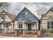Charming blue and white two-story home with peaked roof and inviting front porch behind black iron fence at 160 W Bayaud Ave, Denver, CO 80223