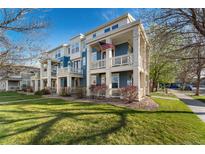 Inviting two-story townhome featuring a charming blue exterior and a welcoming front porch with an American flag at 9478 E 108Th Ave, Commerce City, CO 80640