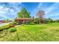 Charming brick home with lush landscaping, mature trees, and a well-manicured lawn at 2901 Monaco Pkwy, Denver, CO 80207