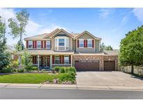 Inviting two-story home featuring a covered front porch, manicured lawn, and a three-car garage at 19616 E Pinewood Dr, Aurora, CO 80016
