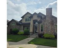 Charming two-story home features a brick chimney, manicured lawn, and inviting front entrance at 222 S Olive St, Denver, CO 80230