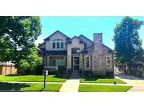 Charming two-story home with lush lawn, manicured landscaping, and inviting front porch at 222 S Olive St, Denver, CO 80230