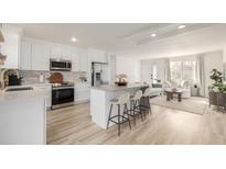 Bright modern kitchen features an island with bar seating, stainless steel appliances, and ample counter space at 16397 E Wyoming Dr, Aurora, CO 80017