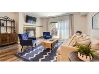 Bright living room with a fireplace, blue chairs, and a sliding glass door to an outdoor space at 7250 Eastmoor Dr # 119, Denver, CO 80237