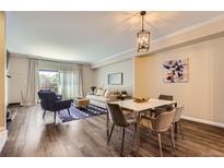 Cozy living room with hardwood floors, comfortable seating, and a dining area under a modern chandelier at 7250 Eastmoor Dr # 119, Denver, CO 80237
