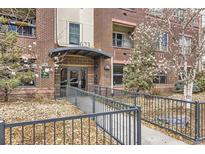 Welcoming entrance of a brick building featuring well-kept landscaping and accessible ramp at 1623 Saint Paul St # 306, Denver, CO 80206