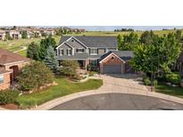 Charming two-story home featuring a landscaped yard, covered porch, and attached two-car garage with brick accents at 10660 Weathersfield Ct, Highlands Ranch, CO 80129
