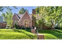 Charming brick home featuring a manicured lawn, beautiful landscaping, and a classic Tudor-style entrance at 926 S Fillmore Way, Denver, CO 80209