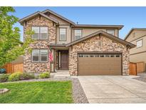 Charming two-story home showcasing a stone facade, attached garage, and well-maintained front yard at 25128 E Maple Ave, Aurora, CO 80018