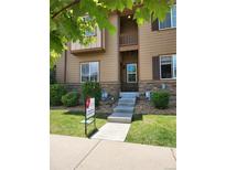 Inviting two-story townhome with a private balcony, stone accents, and manicured lawn at 1211 Bistre St, Longmont, CO 80501