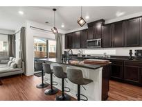 Modern kitchen featuring dark cabinetry, granite countertops, an island with bar seating, and stainless steel appliances at 10226 Worchester St, Commerce City, CO 80022