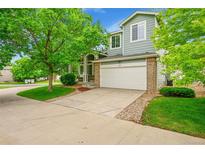 Charming two-story home with a brick-accented garage, well-manicured lawn, and mature trees at 10571 Garfield St, Thornton, CO 80233