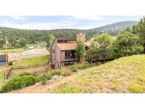 Secluded home featuring mature trees, multi-car garage, and a stone chimney at 3260 Bit Rd, Evergreen, CO 80439