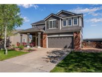 Charming two-story home with a well-manicured lawn, a two-car garage, and a welcoming front porch at 14803 E 119Th Ave, Commerce City, CO 80603