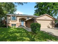 Charming two-story home with manicured lawn, brick accents, attached garage, and inviting blue front door at 6742 Cole Cir, Arvada, CO 80004